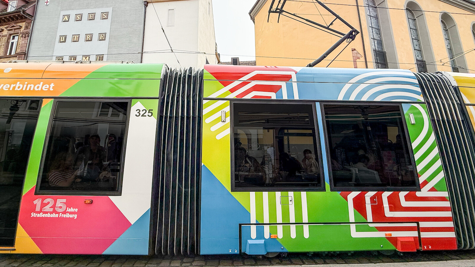 Bunt beklebte Straßenbahn „125 Jahre Straßenbahn Freiburg“ mit geometrischem Streifenmuster, Nahaufnahme des Wagens 325